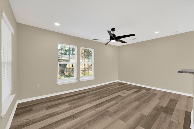 unfurnished room featuring baseboards, wood finished floors, and recessed lighting