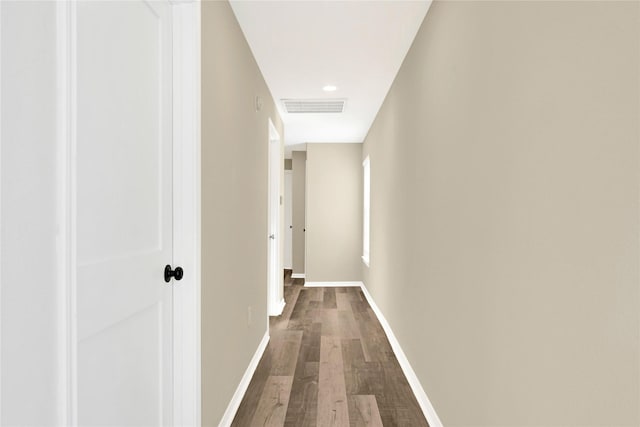 hall with visible vents, baseboards, and wood finished floors