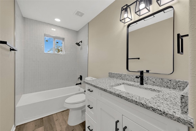 full bath with shower / bathtub combination, toilet, wood finished floors, visible vents, and vanity