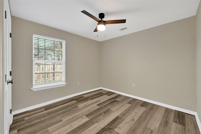 unfurnished room featuring baseboards, visible vents, ceiling fan, and wood finished floors