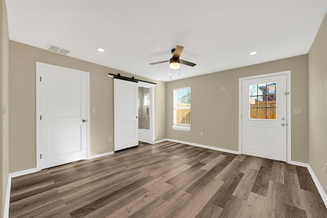 interior space with dark wood-style flooring, visible vents, baseboards, and a barn door