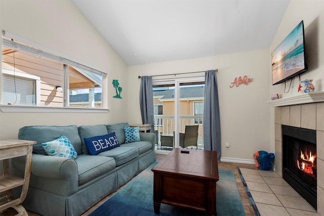 living room with tile patterned flooring, baseboards, vaulted ceiling, and a tiled fireplace