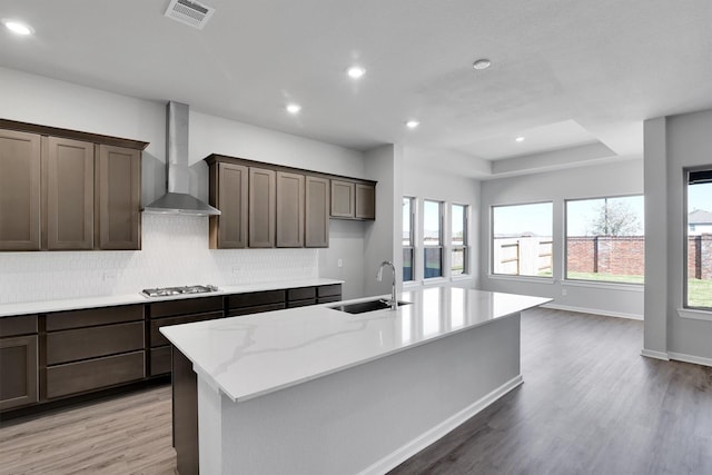 2920 Apple Rose, Katy, TX 77493 - kitchen with visible vents, a kitchen island with sink, a sink, wall chimney exhaust hood, and light wood finished floors