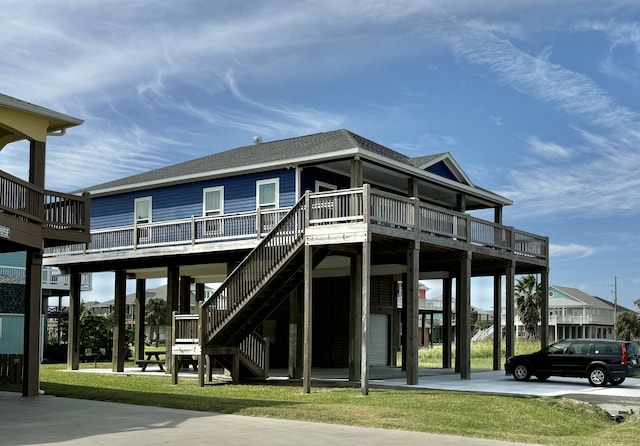 exterior space with a shingled roof, stairway, a front lawn, and a carport