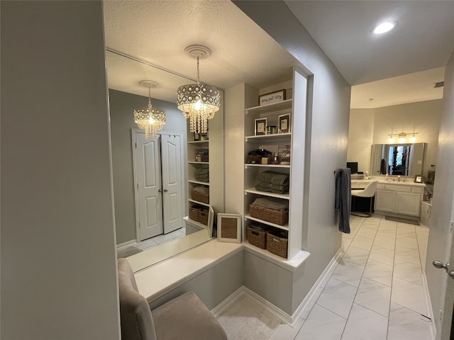 hall featuring a chandelier, recessed lighting, marble finish floor, and baseboards