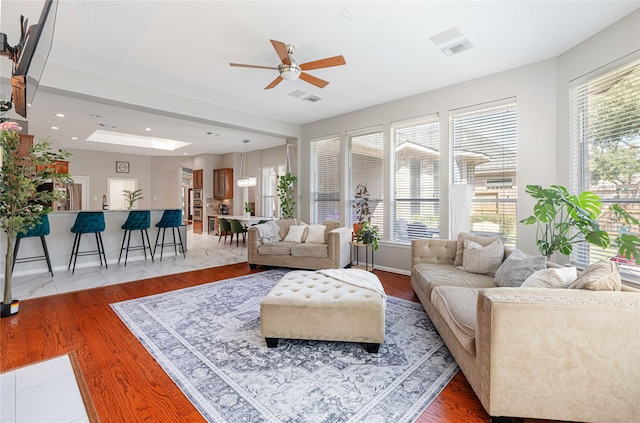 living room featuring light wood-type flooring, a wealth of natural light, visible vents, and a skylight