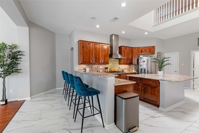 kitchen with arched walkways, marble finish floor, stainless steel appliances, visible vents, and wall chimney exhaust hood