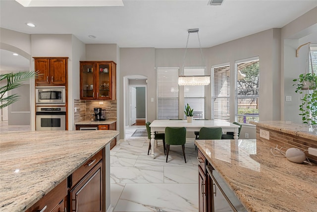 kitchen with marble finish floor, appliances with stainless steel finishes, arched walkways, and decorative backsplash