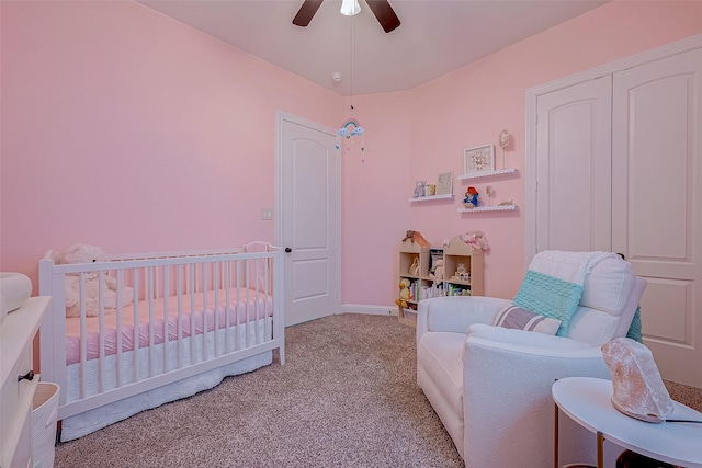 bedroom featuring light carpet, a nursery area, and a ceiling fan