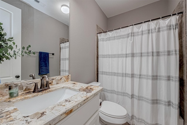 full bath with toilet, a textured wall, vanity, and visible vents