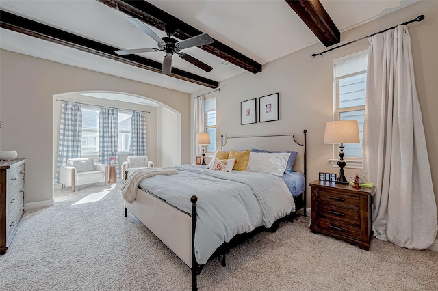 bedroom featuring light carpet, baseboards, a ceiling fan, and beamed ceiling