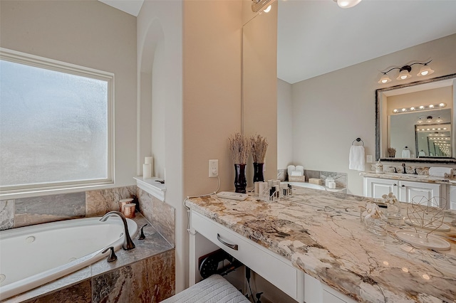 bathroom with a healthy amount of sunlight, a garden tub, and vanity