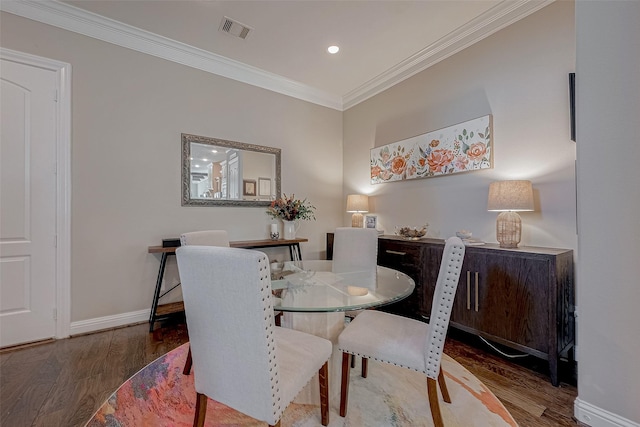 dining area with baseboards, visible vents, ornamental molding, and wood finished floors