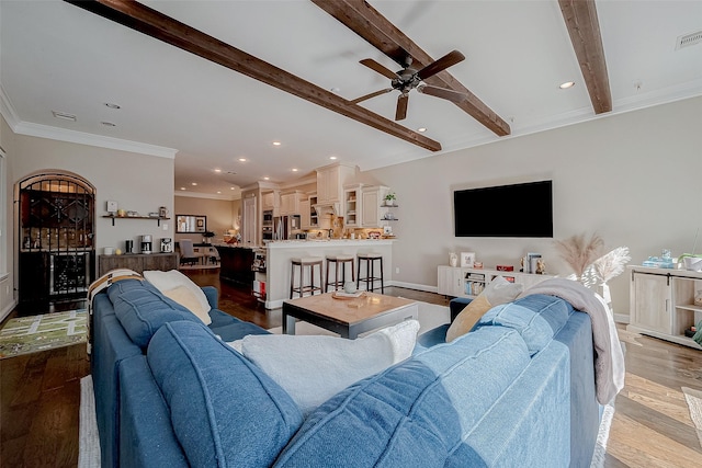 living room with beam ceiling, crown molding, light wood-style flooring, and baseboards