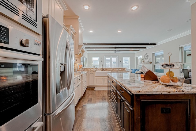 kitchen featuring dark brown cabinetry, white cabinetry, ornamental molding, appliances with stainless steel finishes, and light wood-type flooring