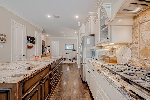 kitchen featuring visible vents, white cabinets, glass insert cabinets, crown molding, and gas cooktop