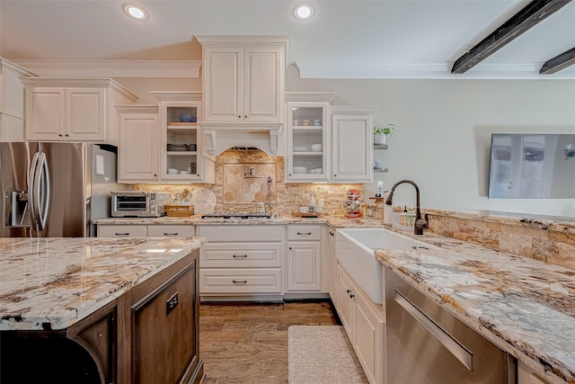 kitchen featuring crown molding, stainless steel appliances, glass insert cabinets, white cabinets, and a sink