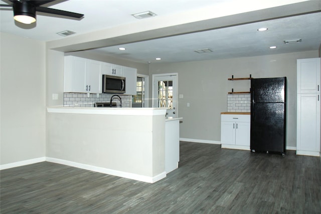 kitchen with light countertops, freestanding refrigerator, stainless steel microwave, and white cabinetry