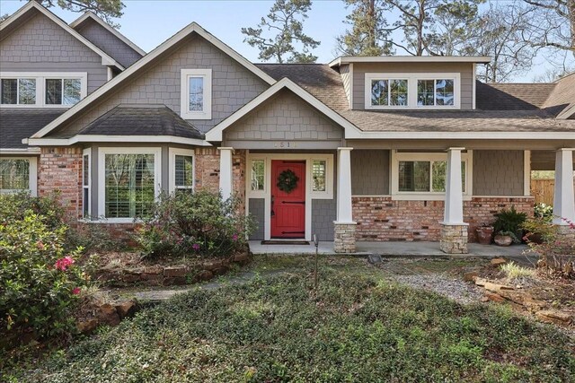 craftsman-style home featuring brick siding and a shingled roof