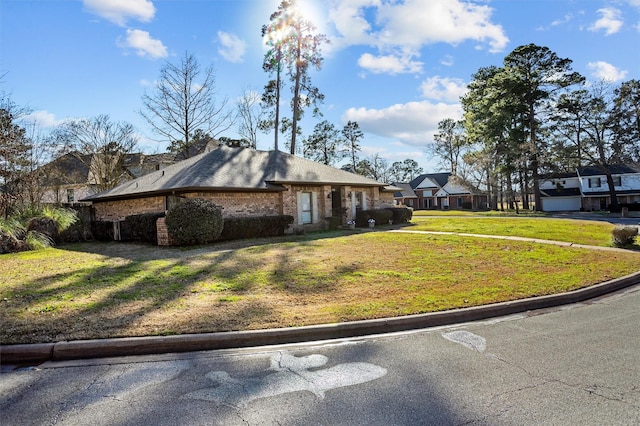 exterior space with brick siding, a front lawn, and a residential view