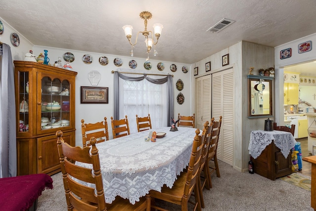 dining room featuring visible vents, a notable chandelier, light carpet, and a textured ceiling