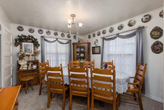 carpeted dining area featuring a textured ceiling, baseboards, and a notable chandelier