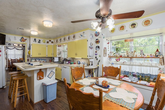 kitchen with white appliances, dark wood finished floors, a kitchen island, light countertops, and a textured ceiling