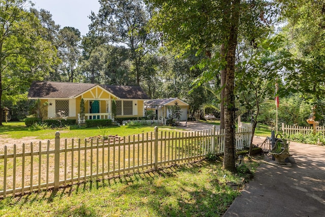 ranch-style home featuring driveway, a fenced front yard, a garage, and a front yard