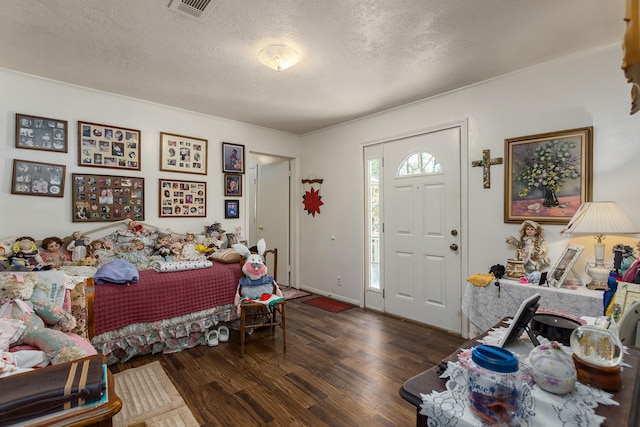 entrance foyer featuring dark wood-style floors, a textured ceiling, visible vents, and baseboards