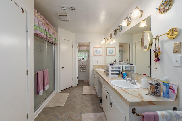 bathroom with double vanity, a shower stall, visible vents, and a sink