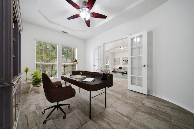 office space with a tray ceiling, french doors, arched walkways, visible vents, and baseboards