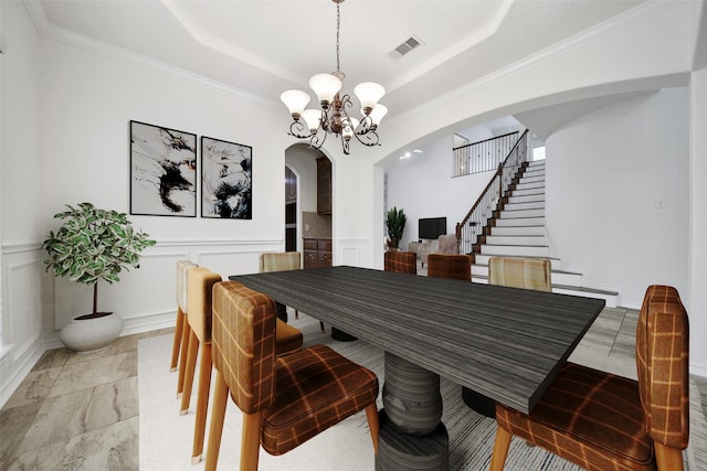 dining area featuring visible vents, arched walkways, an inviting chandelier, a tray ceiling, and a decorative wall