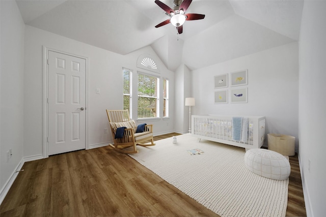 bedroom featuring a ceiling fan, vaulted ceiling, wood finished floors, a nursery area, and baseboards