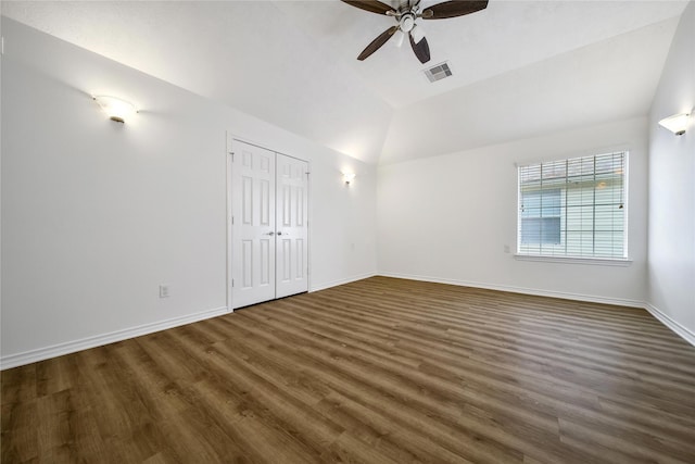 unfurnished room with lofted ceiling, dark wood-style floors, visible vents, and baseboards