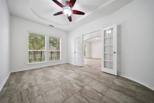 spare room with visible vents, arched walkways, a raised ceiling, baseboards, and french doors