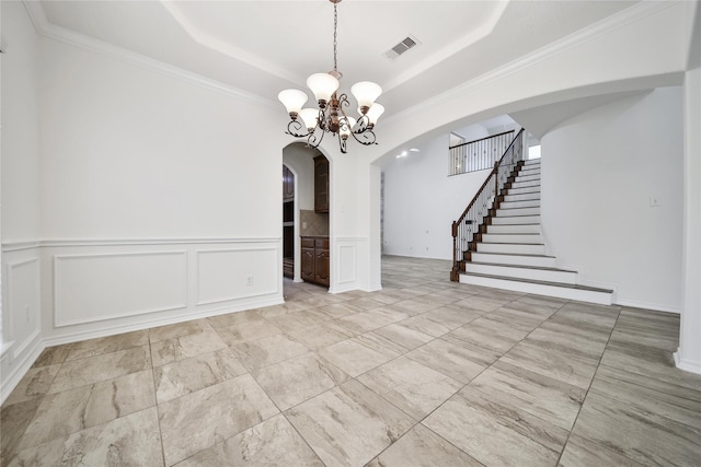 unfurnished dining area featuring arched walkways, a raised ceiling, visible vents, a decorative wall, and an inviting chandelier