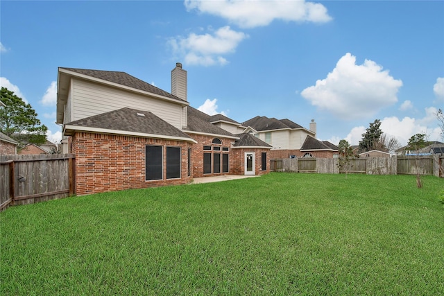 back of property with brick siding, a lawn, and a fenced backyard