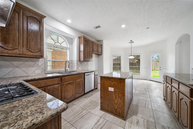 kitchen featuring arched walkways, dark stone counters, a sink, a center island, and dishwasher