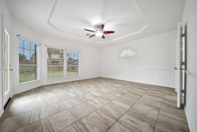 unfurnished room with a ceiling fan, a tray ceiling, and baseboards