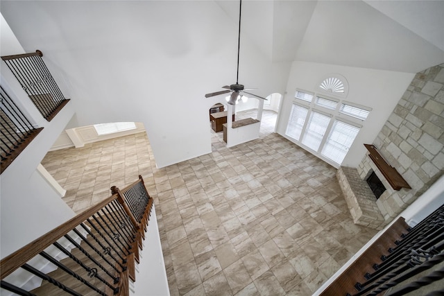 living room featuring ceiling fan, high vaulted ceiling, and a fireplace