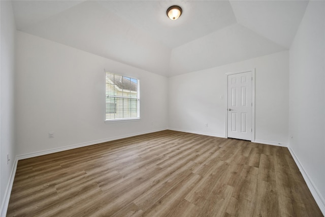 empty room with light wood-type flooring, baseboards, and lofted ceiling