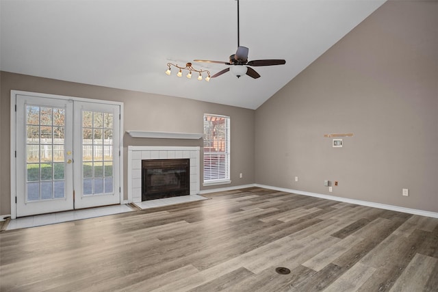 unfurnished living room with light wood-type flooring, a tile fireplace, and baseboards