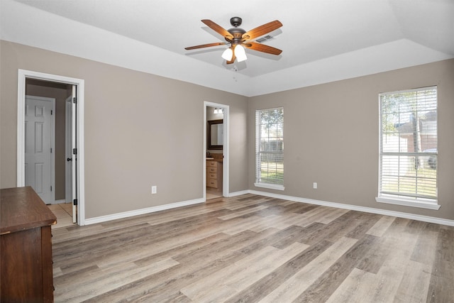 spare room featuring ceiling fan, lofted ceiling, light wood-style flooring, and baseboards