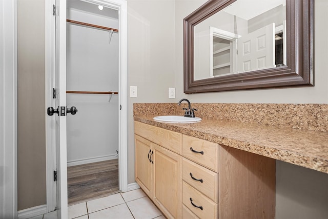 bathroom featuring a spacious closet, tile patterned flooring, vanity, and baseboards