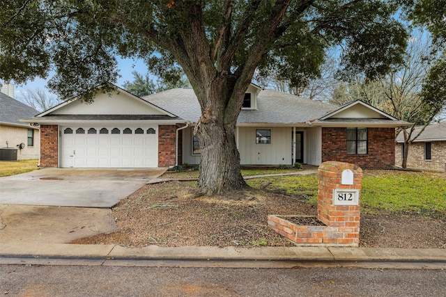 ranch-style home featuring central AC unit, driveway, brick siding, and an attached garage