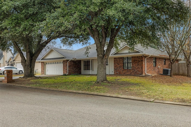 single story home featuring a garage, brick siding, a front lawn, and central air condition unit