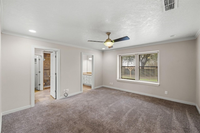 unfurnished bedroom featuring a textured ceiling, light carpet, baseboards, ensuite bath, and crown molding