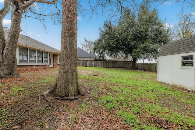 view of yard with a fenced backyard, an outdoor structure, and a storage unit