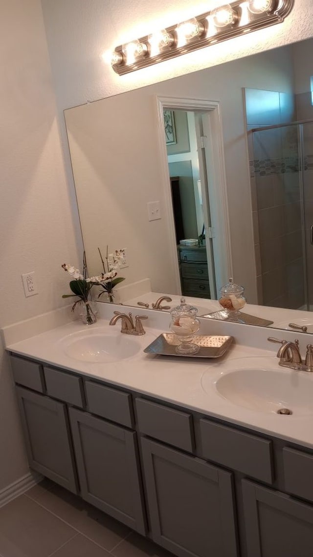 bathroom featuring double vanity, tile patterned floors, a sink, and a shower stall