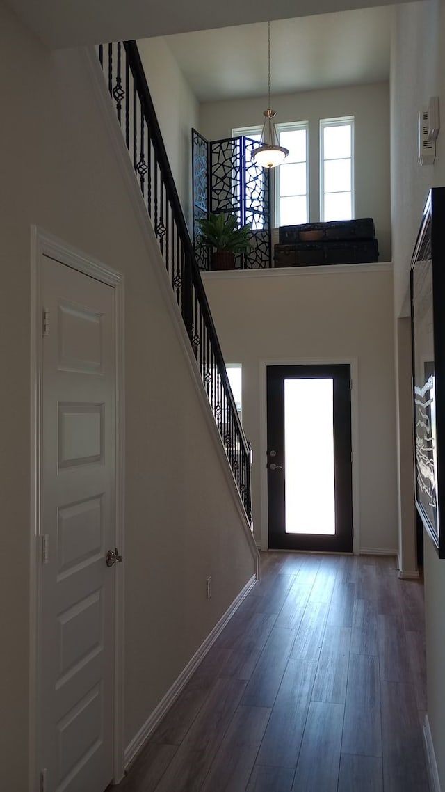 entryway featuring stairway, dark wood-style flooring, a towering ceiling, and baseboards